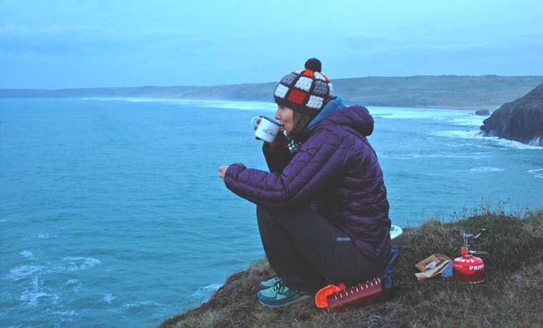 Woman drinking coffee on sea cliffs