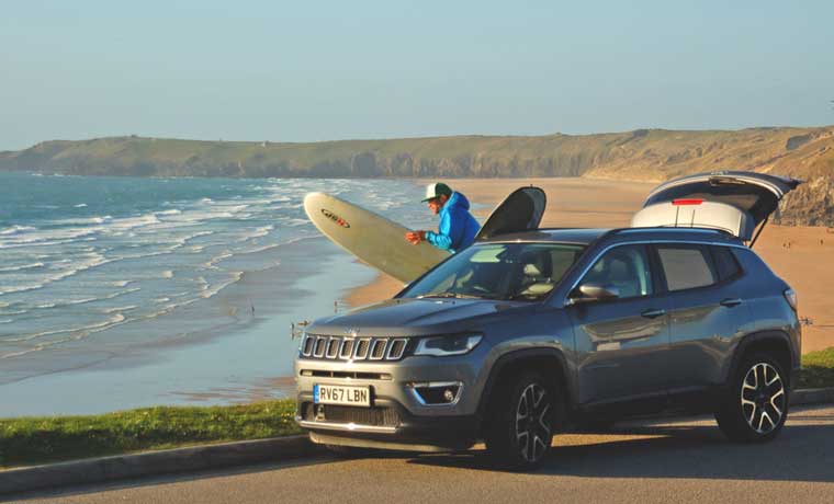 Surfer unpacking jeep with board