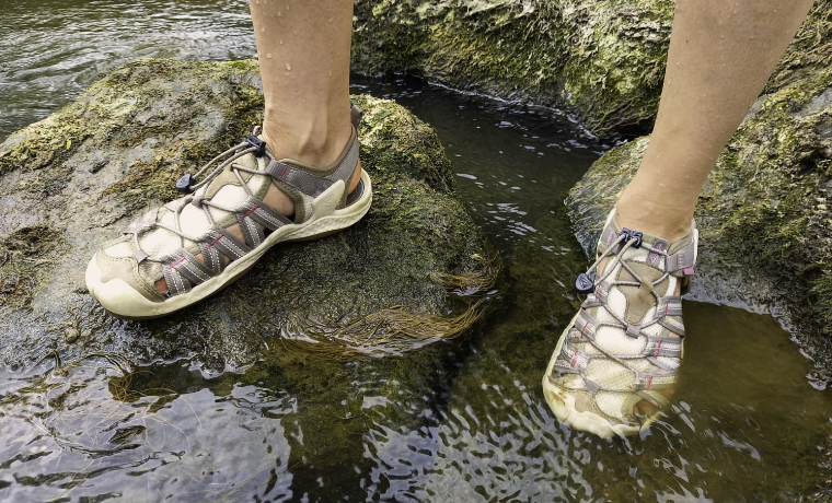 Woman standing in river wearing water shoes for hiking