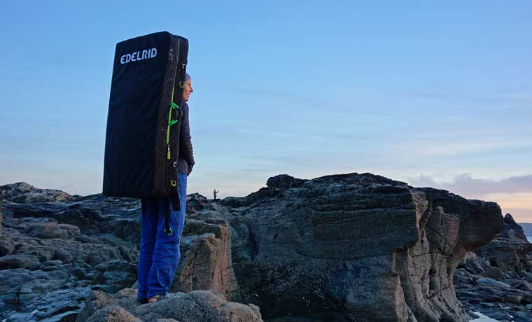 Woman carrying bouldering mat on back