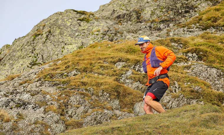 Man running on trail in orange jacket
