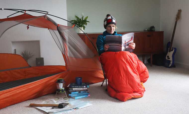 Woman reading next to tent indoors