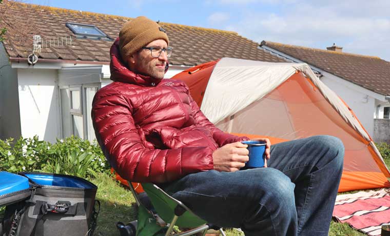 Man sitting by tent in backyard