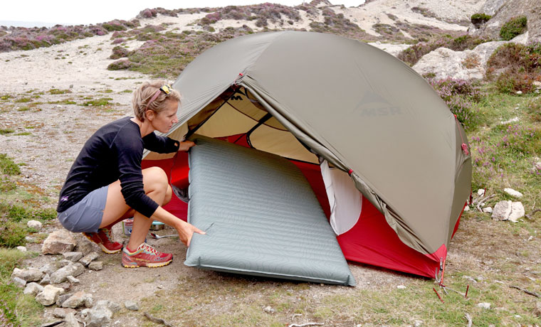 Woman putting air bed in tent