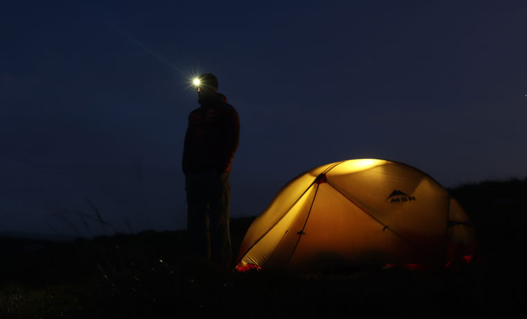 Man next to tent at night