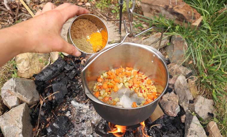 Pouring spices into campfire curry
