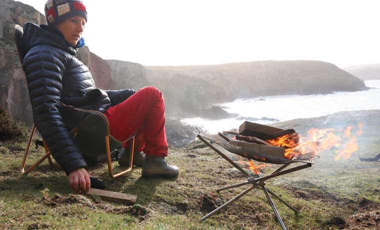 Woman sitting on cliffs with fire pit