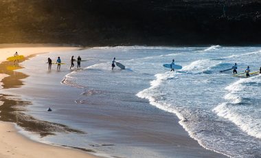 People getting in the sea to surf