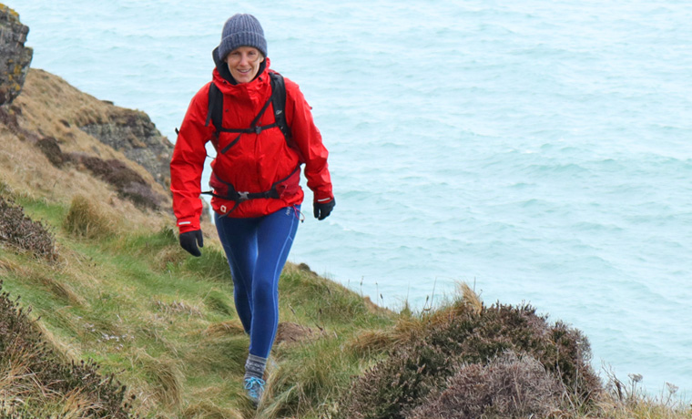 Woman hiking in red jacket on coast