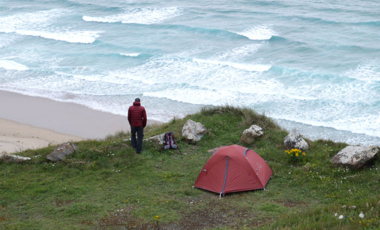 Man looking out to sea next to tent