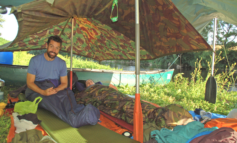 Man sitting under canoe camping tarp