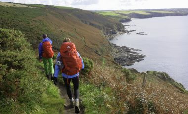 Two people hiking in Cornwall on the coast