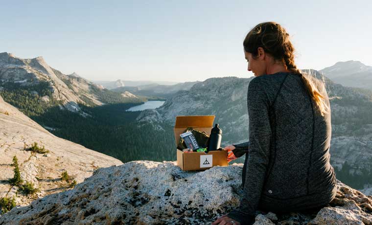 Woman-sitting-on-rocks-with-adventure-box