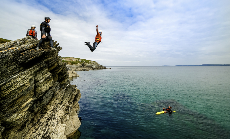 Person jumping off a rock into the sea