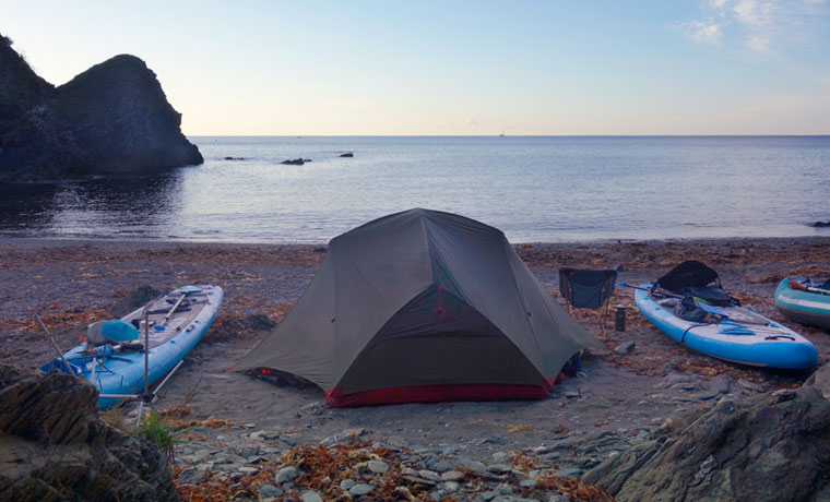 Tent and paddleboards on the beach