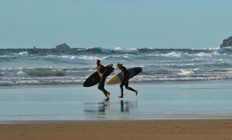 Surfers running across the beach
