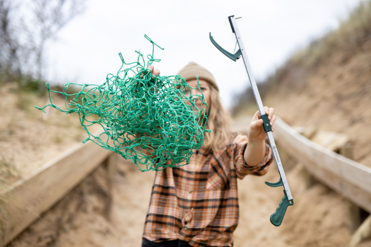Woman holding litter picker and ghost net