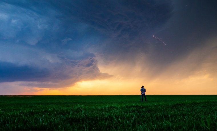 Man in field watching storm